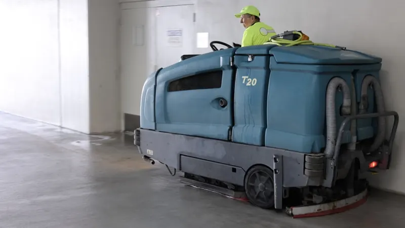 Ride-on floor scrubber cleaning a concrete garage floor