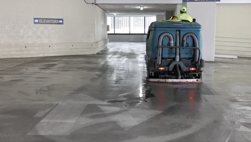 Ride-on power scrubber cleaning a parking garage floor