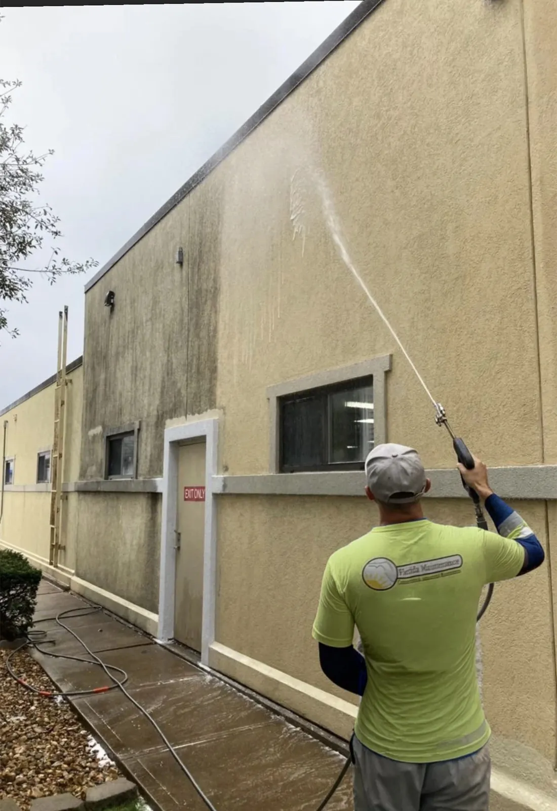 Florida Maintenance crew low-pressure washing a stucco building wall