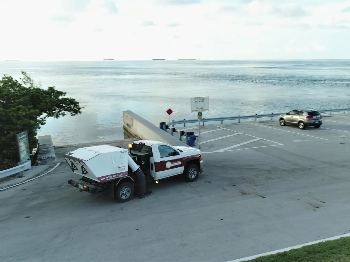Florida Maintenance sweeper servicing an open paved lot near a waterfront dock