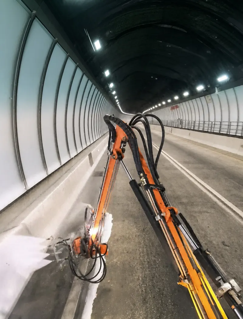 Hydraulic boom cleaning a highway barrier wall
